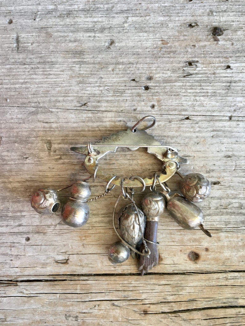 May include: A silver charm bracelet with a variety of charms, including bells, gourds, and a small bird. The bracelet is made of metal and has a clasp closure.