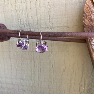 May include: A pair of silver earrings with light purple gemstone accents.