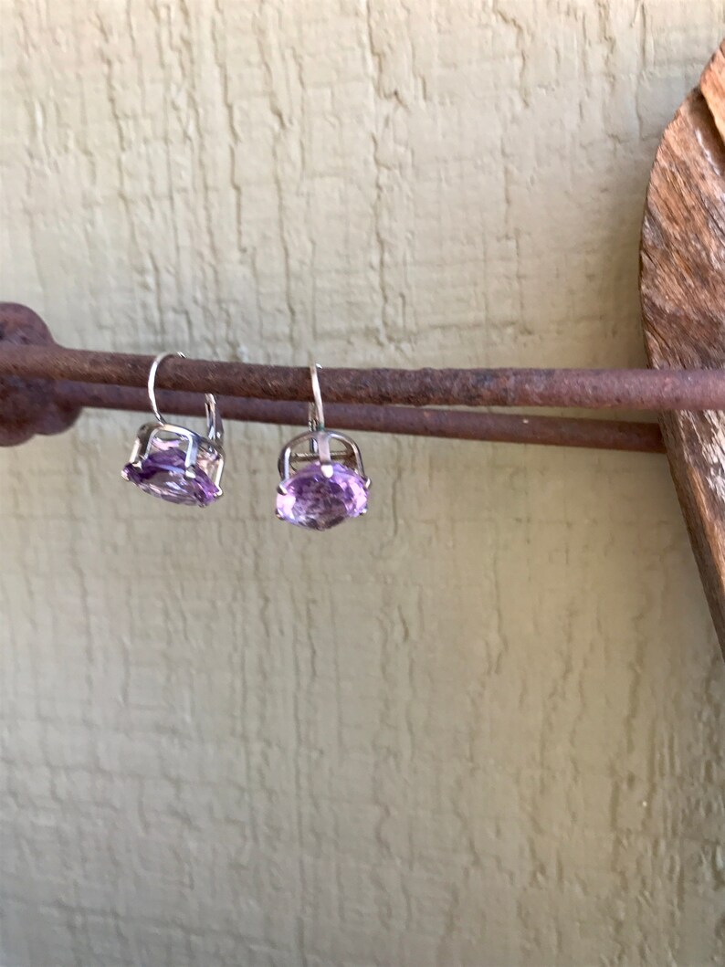 May include: A pair of silver earrings with light purple gemstone accents.
