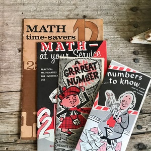Peut inclure: Trois livres de mathématiques vintage aux couvertures colorées. Le livre du haut est brun avec le texte "MATH time-savers 12". Le livre du milieu est rouge et noir avec le texte "MATH- at your Service" et un personnage de dessin animé portant un kilt. Le livre du bas est rouge et blanc avec le texte "numbers to know A HANDY GUIDE TO WEIGHTS AND MEASURES" et un personnage de dessin animé assis sur un tabouret.