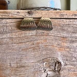 May include: Two hammered gold-tone metal earrings in a triangular shape.