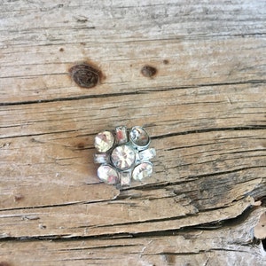 May include: A silver-toned brooch with clear rhinestones arranged in a geometric pattern.