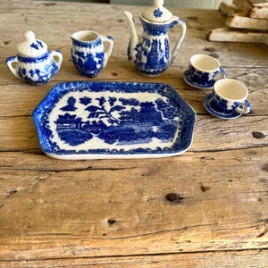 May include: A blue and white porcelain tea set with a teapot, creamer, sugar bowl, two teacups and saucers, and a matching tray. The set features a traditional willow pattern.