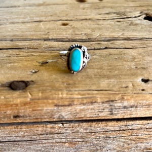 May include: A silver ring with a turquoise oval stone set in a decorative design.