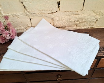 Lot de quatre jolies serviettes blanches vintage avec un motif bouton de rose