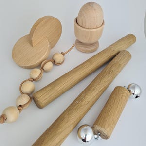 May include: Wooden baby toy with a rattle, a teether, and a set of bells. The toy is made of natural wood and has a simple design.