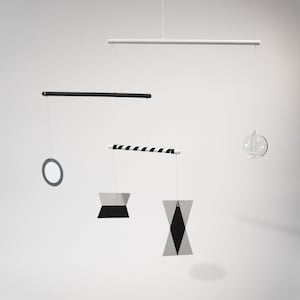 Puede incluir: Un móvil blanco y negro con una varilla de madera rayada, una forma geométrica blanca y negra, un círculo y una esfera de vidrio transparente.