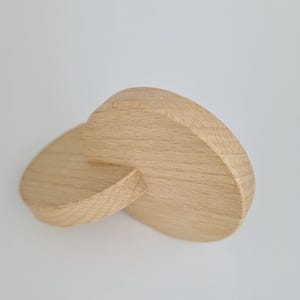 Può includere: Due cerchi di legno, uno leggermente più piccolo dell'altro, sono intrecciati. I cerchi sono in legno chiaro e hanno una finitura liscia e naturale.