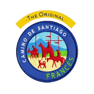Può includere: Toppa ricamata con un design circolare blu con la scritta "CAMINO DE SANTIAGO FRANCES". La toppa include uno striscione giallo con la scritta ".THE ORIGINAL." All'interno del cerchio ci sono figure rosse di persone e animali.