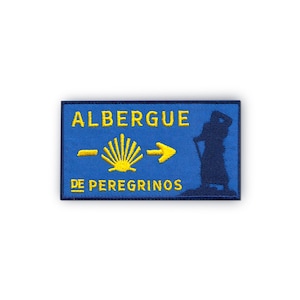 May include: Blue and yellow embroidered patch with the text "Albergue de Peregrinos" and a pilgrim symbol.