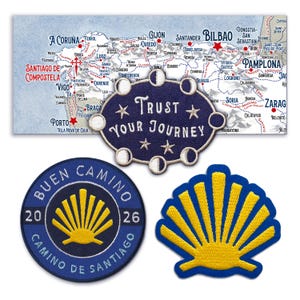 Op de afbeelding: Afbeelding van drie geborduurde patches en een kaart van Spanje. De kaart toont de pelgrimsroute van de Camino de Santiago. Eén patch is rond met de tekst "BUEN CAMINO" en een gele schelp. Een andere patch is ovaal met de tekst "TRUST YOUR JOURNEY".