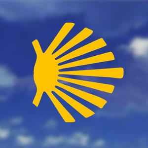 May include: A yellow scallop shell design with radiating lines, set against a blue background. The shell is a symbol of the Camino de Santiago pilgrimage route, often used on merchandise like stickers, patches, and apparel.
