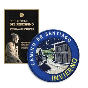 Op de afbeelding: Een zwarte en gouden Credencial del Peregrino-kaart en een blauwe Camino de Santiago-patch. De kaart heeft tekst in het Spaans en een afbeelding van een standbeeld. De patch toont een nachtscène met gebouwen en de woorden "Camino de Santiago Invierno."