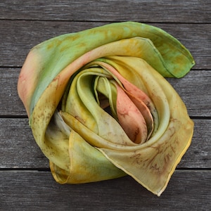 square handpainted Silkscarf in shades of yellow, red, brown and green