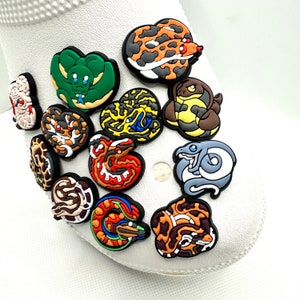 May include: A set of 12 colorful snake shoe charms, featuring various snake designs with different colors and patterns. The charms are made of rubber and are designed to be attached to shoes.