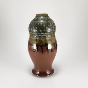 May include: A brown ceramic vase with a green and brown glaze. The vase has a rounded body and a flared lip.