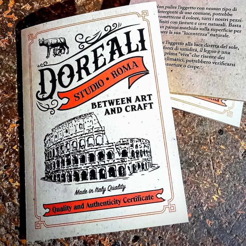 May include: A vintage-style logo for Doreali Studio Roma, featuring a black and white illustration of the Colosseum, with the text "Between Art and Craft" and "Made in Italy Quality".