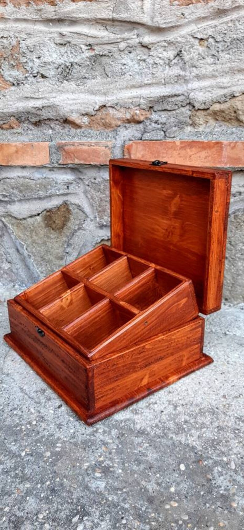 May include: A wooden box with a hinged lid and multiple compartments. The box is stained a rich reddish-brown colour.