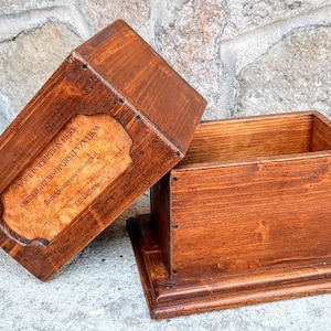 May include: A wooden box with a hinged lid. The lid has a label that reads "THE COLLECTION BOX - SUPERIOR HANDCRAFTED TIMBER - MADE IN AUSTRALIA".