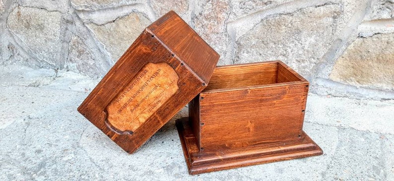 May include: A wooden box with a hinged lid. The lid has a label that reads "THE COLLECTION BOX - SUPERIOR HANDCRAFTED TIMBER - MADE IN AUSTRALIA".