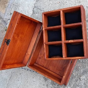 May include: A wooden box with a hinged lid and a compartment with six individual slots lined with black fabric. The box is stained a rich brown colour.