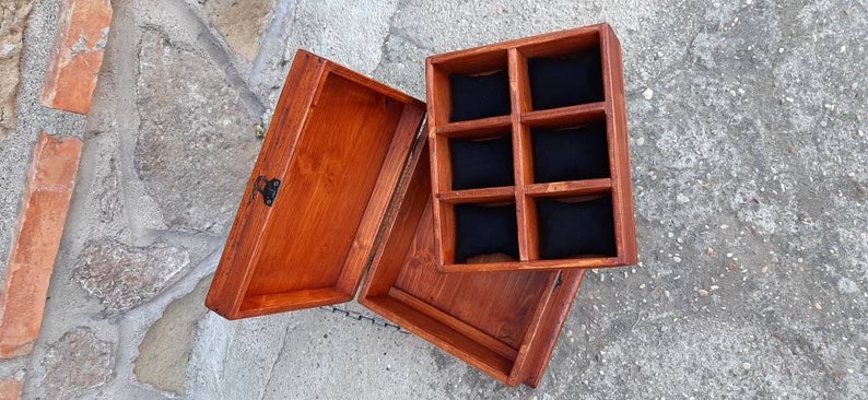 May include: A wooden box with a hinged lid and a compartment with six individual slots lined with black fabric. The box is stained a rich brown colour.