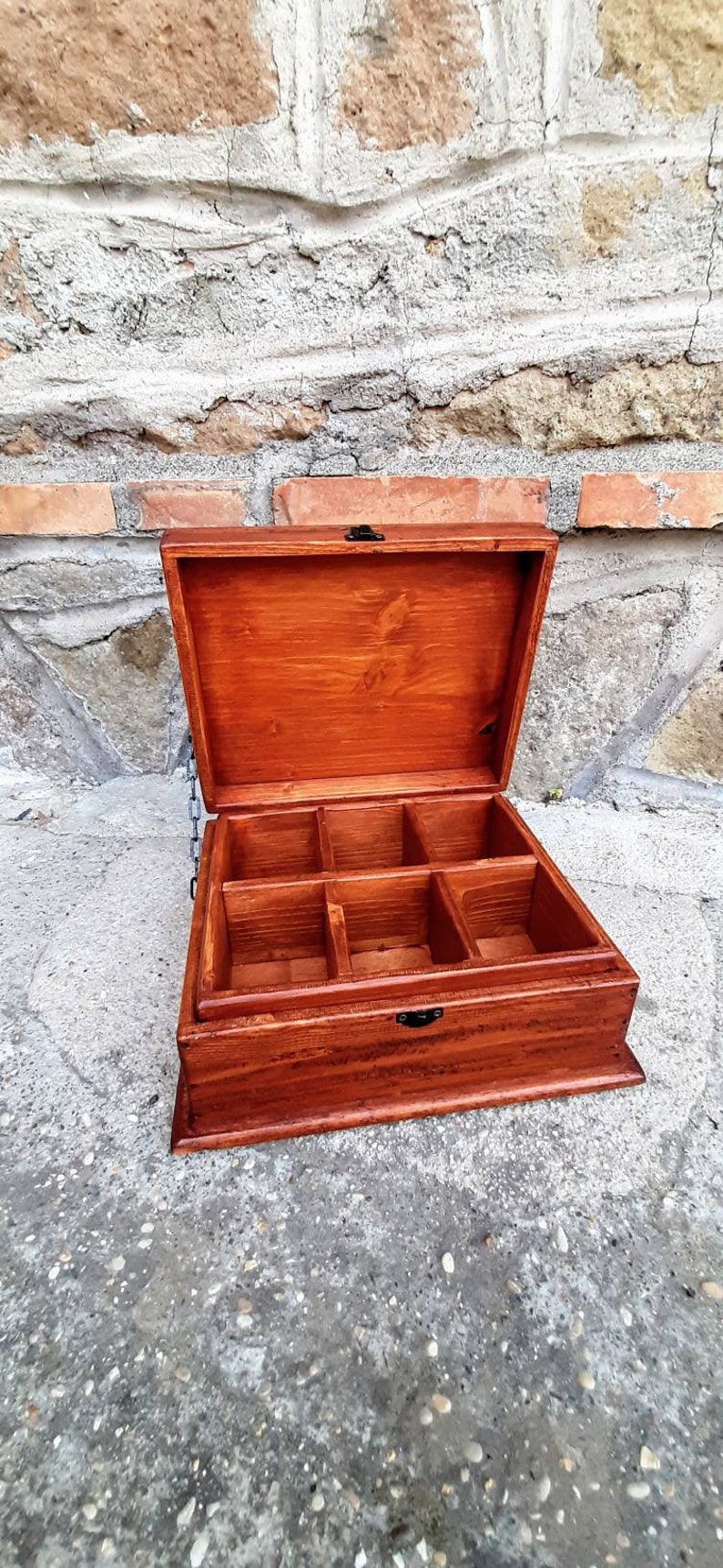 May include: A wooden box with a hinged lid and multiple compartments. The box is stained a rich reddish-brown colour and has black metal hinges.