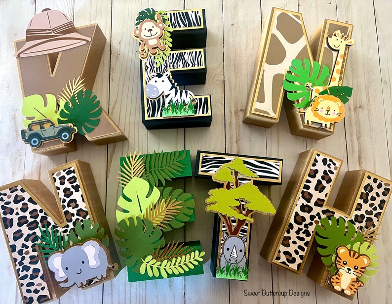 Puede incluir: Un conjunto de letras de madera decorativas que deletrean "WELCOME", cada una adornada con dise&ntilde;os tem&aacute;ticos de la jungla. Las letras presentan estampados de animales de safari, sombreros de safari y follaje de la jungla, con recortes de animales.