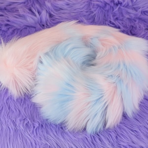May include: A close-up of a soft, fluffy fabric in shades of pink and blue. The fabric is arranged in a swirling pattern, creating a visually appealing texture.