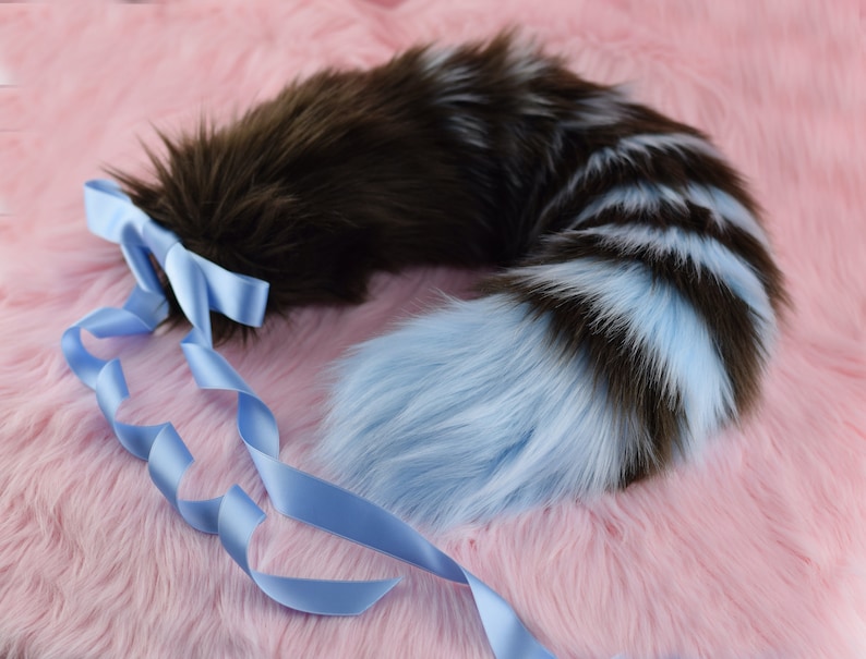 May include: A fluffy brown and blue striped tail with a blue satin ribbon tied around the base.