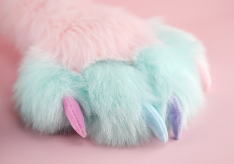 May include: A soft, plush paw with light blue and pink fur and claws. The paw is on a pink background.