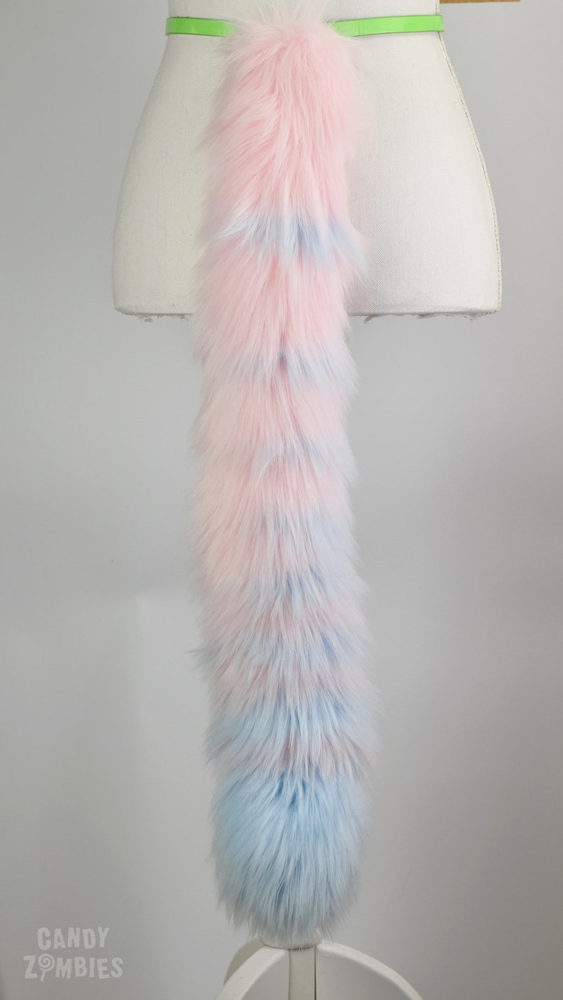 May include: A long, fluffy pink and blue faux fur tail with a light green belt around the waist.
