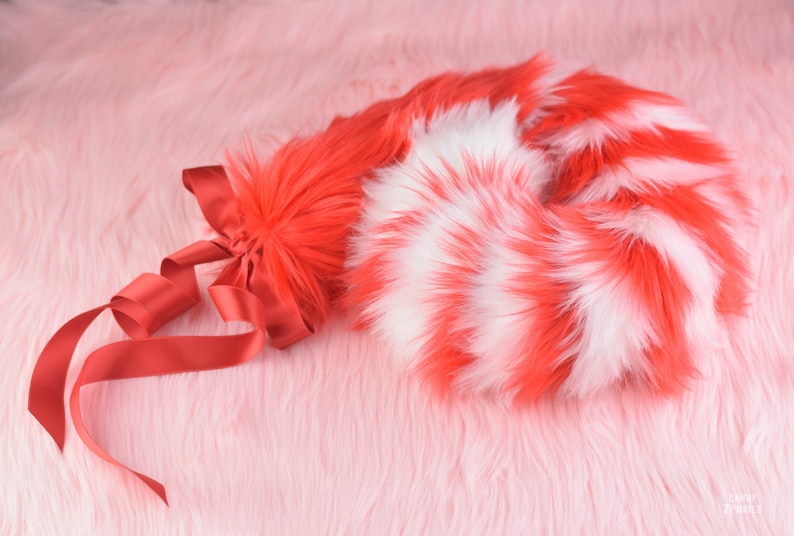 May include: A red and white striped fluffy tail with a red ribbon tied around the base.