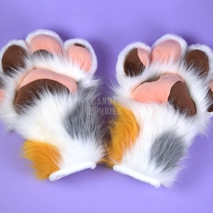 May include: A pair of white, gray, and orange furry paw hand puppets with brown paw pads. The puppets have pink felt accents on the paw pads.