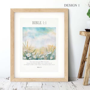 May include: A framed print with the text "BIBLE 1:1" and "DESIGN 1". The artwork features a watercolour landscape with white daisies, tall grass, and a blue and yellow sky. The frame is light brown.