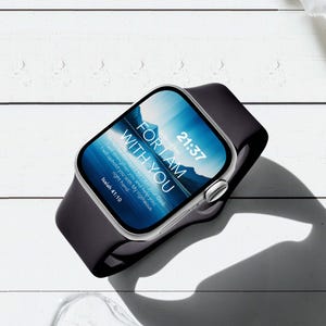May include: A silver smartwatch with a black silicone band. The screen displays the time 21:37 and the text FOR I AM WITH YOU, along with the Bible verse Isaiah 41:10, set against a blue mountain landscape background.