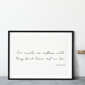 May include: Black framed print with a white background and black text that reads "Our hearts are restless, until They find their rest in You" and "ST AUGUSTINE OF HIPPO" in smaller font.