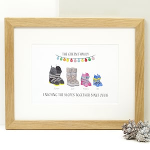 May include: A personalized ski boot family print with the text "The Green Family" and a string of colorful lights above four pairs of ski boots. The boots are labeled "Julian", "Zoe", "Poppy", and "Ollie". The text "Enjoying the slopes together since 2008" is below the boots.