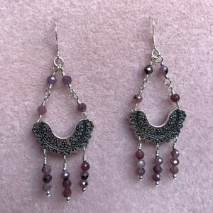May include: A pair of silver earrings with a crescent moon design and dangling purple beads.
