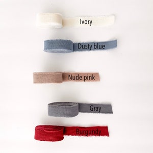 May include: Five spools of fabric ribbon in different colors: ivory, dusty blue, nude pink, gray, and burgundy.