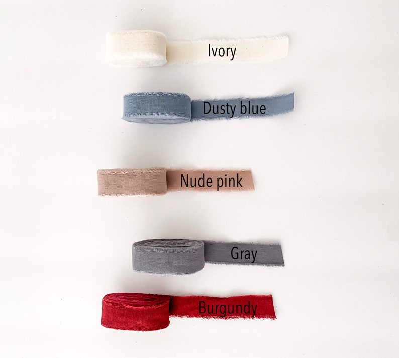 May include: Five spools of fabric ribbon in different colors: ivory, dusty blue, nude pink, gray, and burgundy.