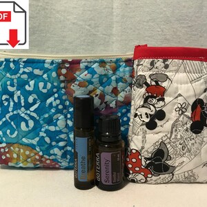 May include: Two quilted zippered pouches, one blue and white with a floral pattern and the other white with a Mickey Mouse print. Three small bottles of essential oils are in front of the pouches. The bottles are labeled "dōTERRA Breathe", "dōTERRA Serenity", and "dōTERRA Serenity".