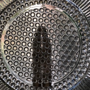May include: A clear glass plate with a decorative hexagonal pattern. The plate has a scalloped edge.