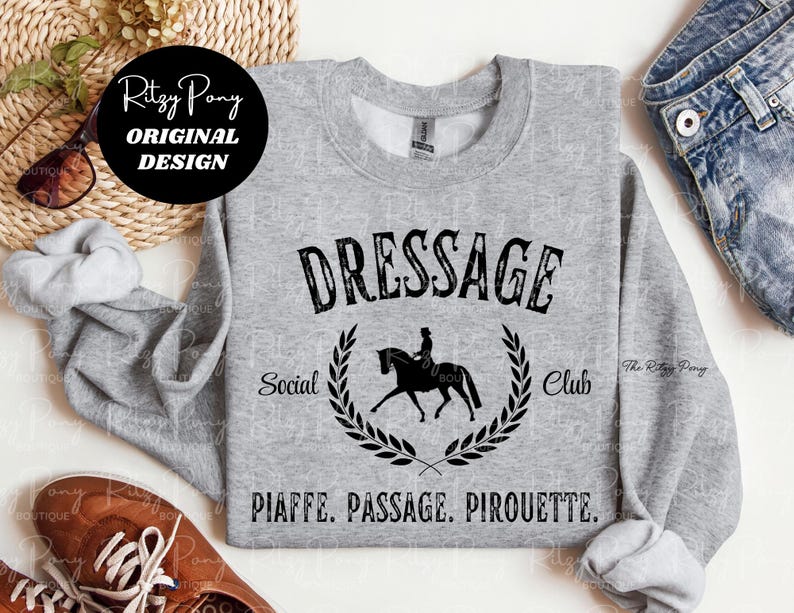 Pu&ograve; includere: Una felpa grigio melange con la scritta nera "DRESSAGE Social Club". Una silhouette nera di un cavallo e un cavaliere &egrave; centrata sotto la parola "DRESSAGE". Le parole "PIAFFE. PASSAGE. PIROUETTE." sono stampate sotto.