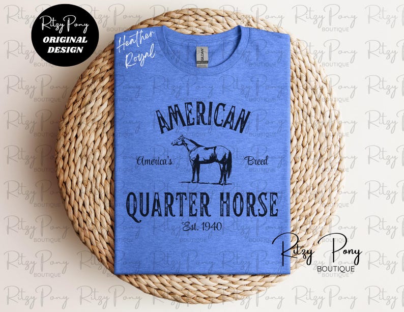 May include: A blue heather t-shirt with a graphic design featuring the words "AMERICAN QUARTER HORSE" and a horse silhouette. The text "America's Breed" and "Est. 1940" are also included. The shirt has a crew neck.