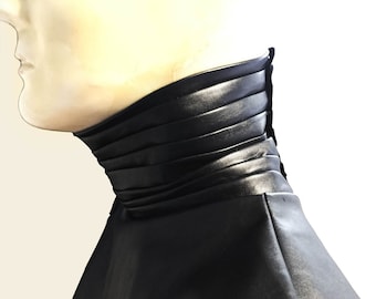 May include: A black leather collar with a pleated design. The collar is folded down and has a smooth, shiny finish.