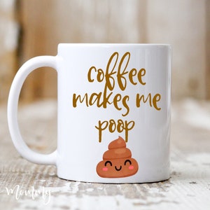 May include: White ceramic coffee mug with the text "coffee makes me poop" in gold lettering. A cartoon poop emoji with a smiling face is below the text. The mug has a curved handle.