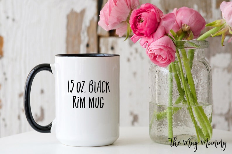 May include: A white ceramic mug with a black handle and black rim. The text 15 oz. Black Rim Mug is printed in black on the front of the mug. The mug has a cylindrical body and a curved handle, providing a clear view of the product's design.