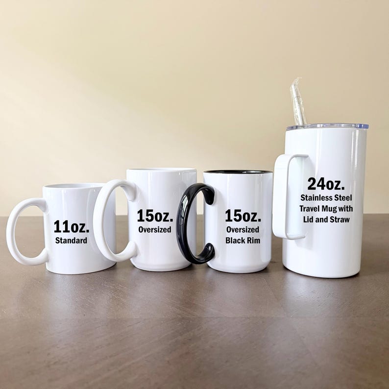 K&ouml;nnte beinhalten: Vier wei&szlig;e Tassen in verschiedenen Gr&ouml;&szlig;en und Ausf&uuml;hrungen. Von links nach rechts: eine 11oz Standardtasse, eine 15oz gro&szlig;e Tasse, eine 15oz gro&szlig;e Tasse mit schwarzem Rand und Henkel sowie ein 24oz Edelstahl-Reisebecher mit Deckel und Trinkhalm.