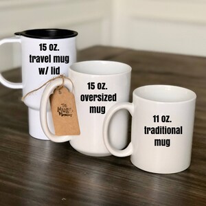 May include: Three white mugs of varying sizes are displayed. The largest is a 15 oz. travel mug with a black lid. A 15 oz. oversized mug and an 11 oz. traditional mug are also shown. Each mug has a handle.